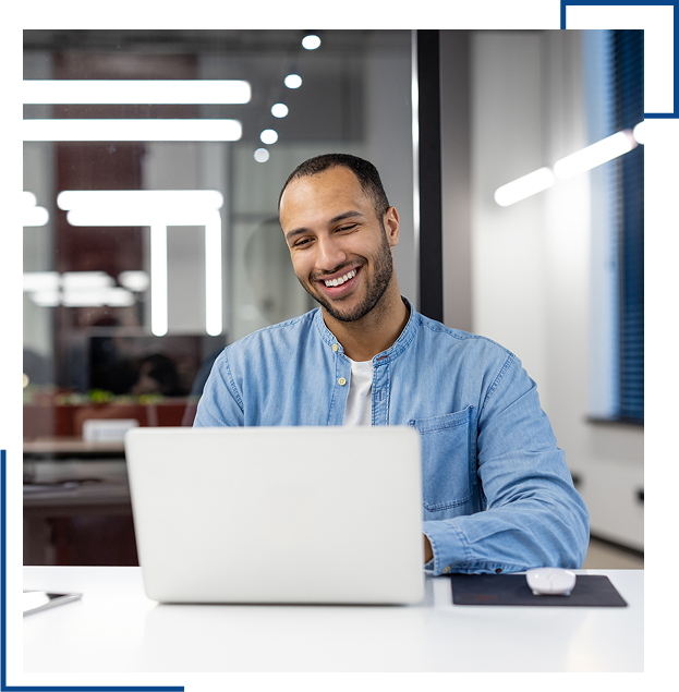 Man smiling while using a laptop.