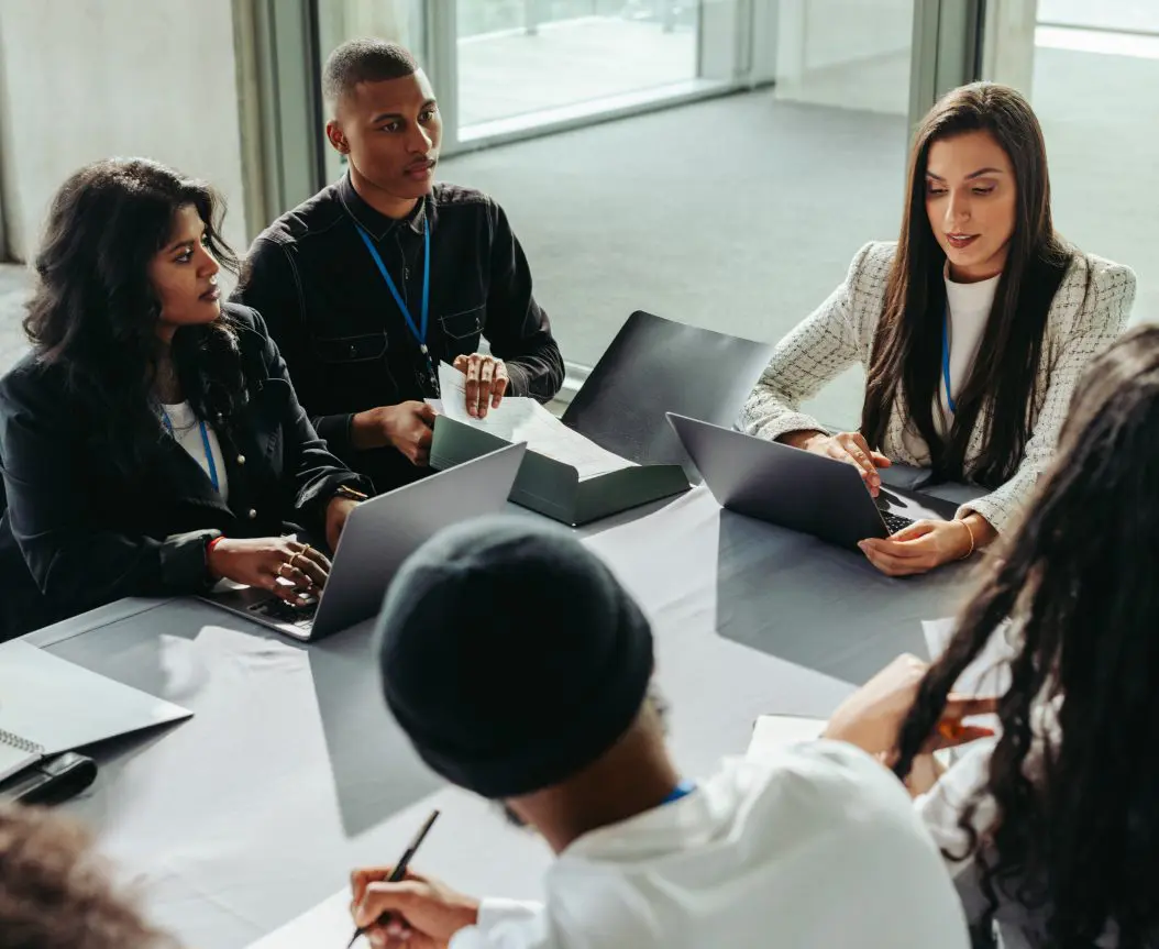 Group meeting with laptops around a table.