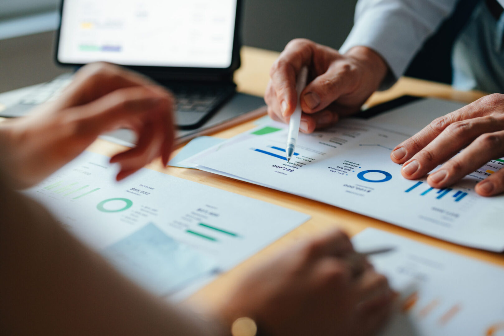 Hands analyzing financial charts on desk.