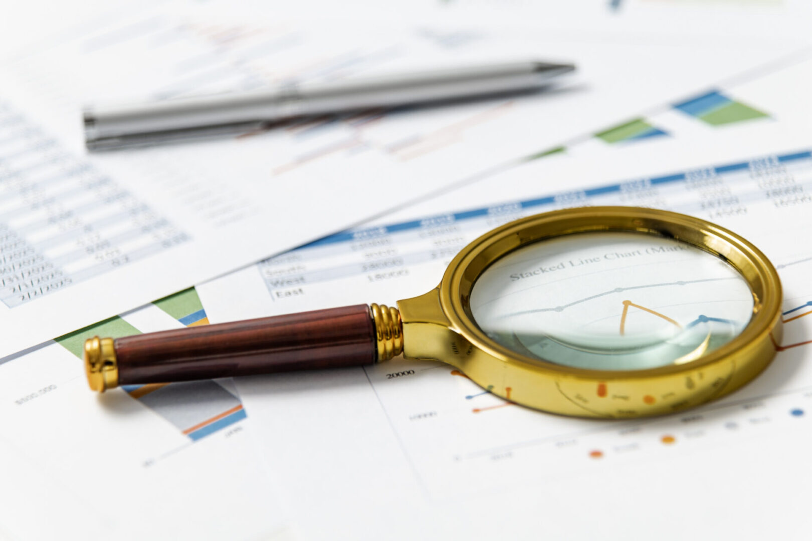 Magnifying glass on financial documents and charts.
